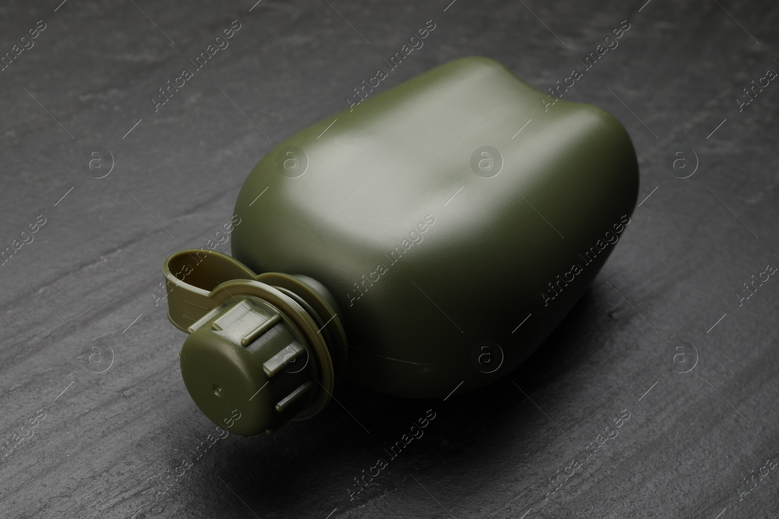 Photo of Green plastic canteen on black table, closeup