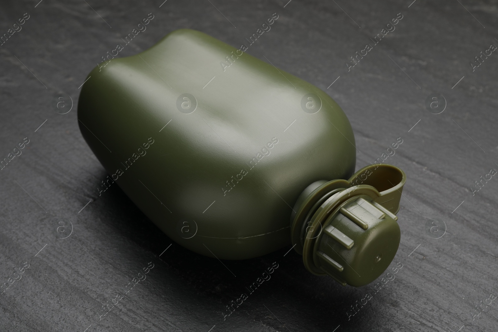 Photo of Green plastic canteen on black table, closeup