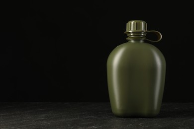 Photo of Green plastic canteen on black table, space for text