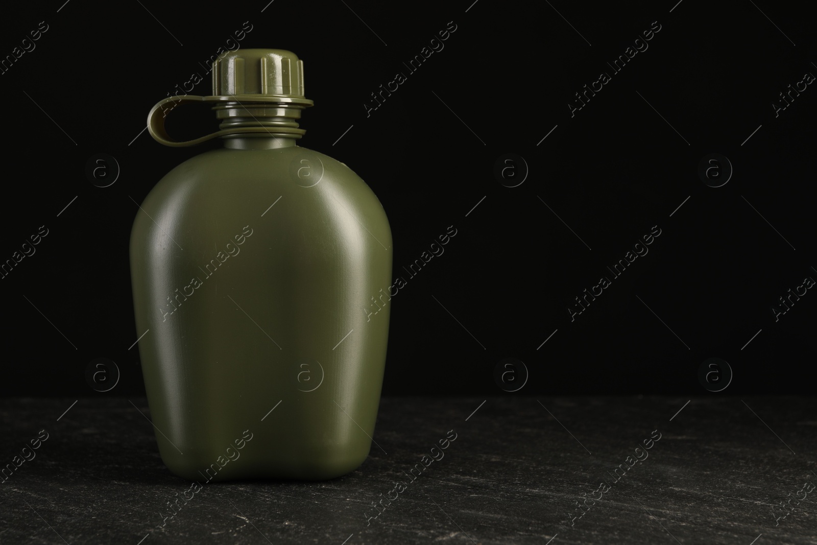 Photo of Green plastic canteen on black table, space for text