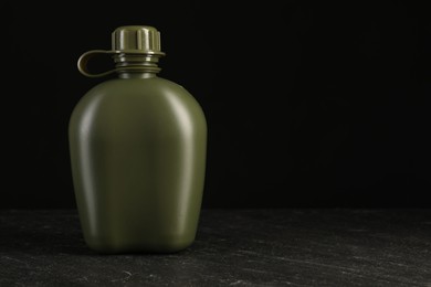 Green plastic canteen on black table, space for text