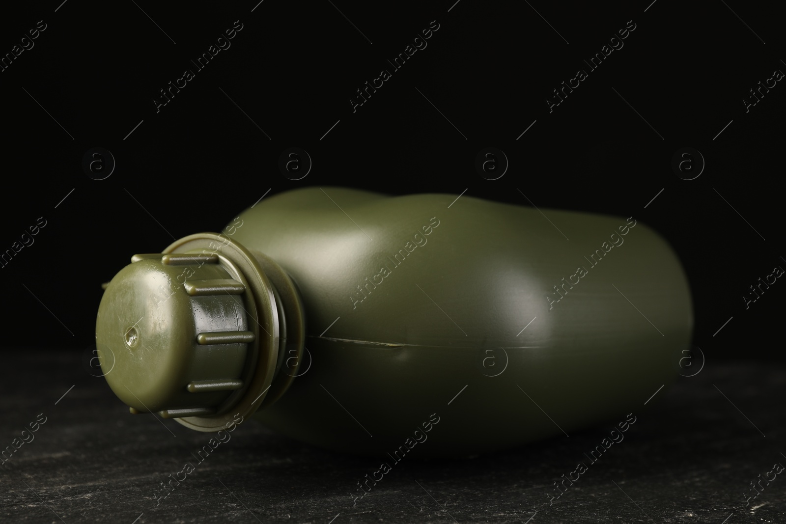 Photo of Green plastic canteen on black table, closeup