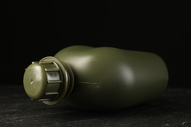 Green plastic canteen on black table, closeup