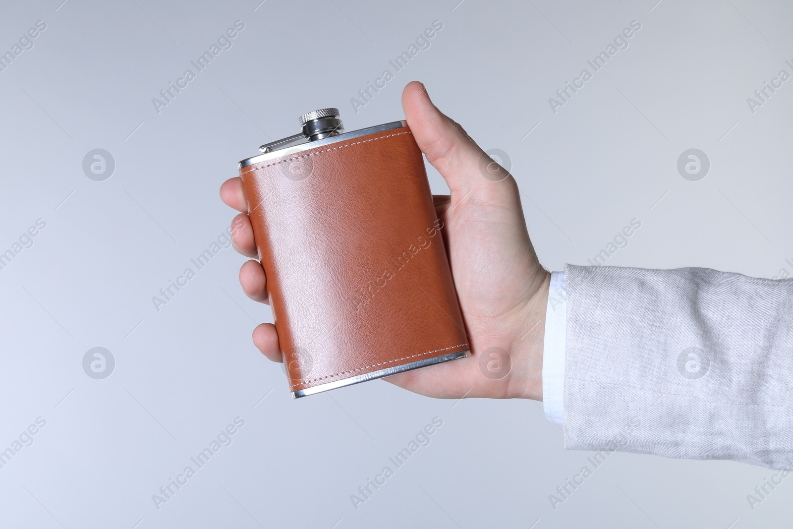 Photo of Man holding new hip flask on light grey background, closeup