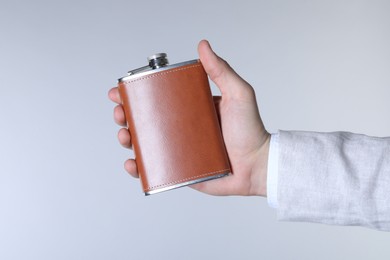 Man holding new hip flask on light grey background, closeup