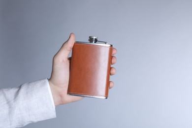 Man holding new hip flask on light grey background, closeup