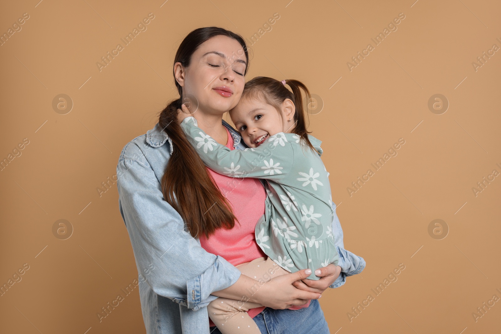 Photo of Portrait of happy mother and her cute little daughter on beige background