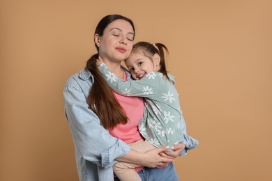 Portrait of happy mother and her cute little daughter on beige background