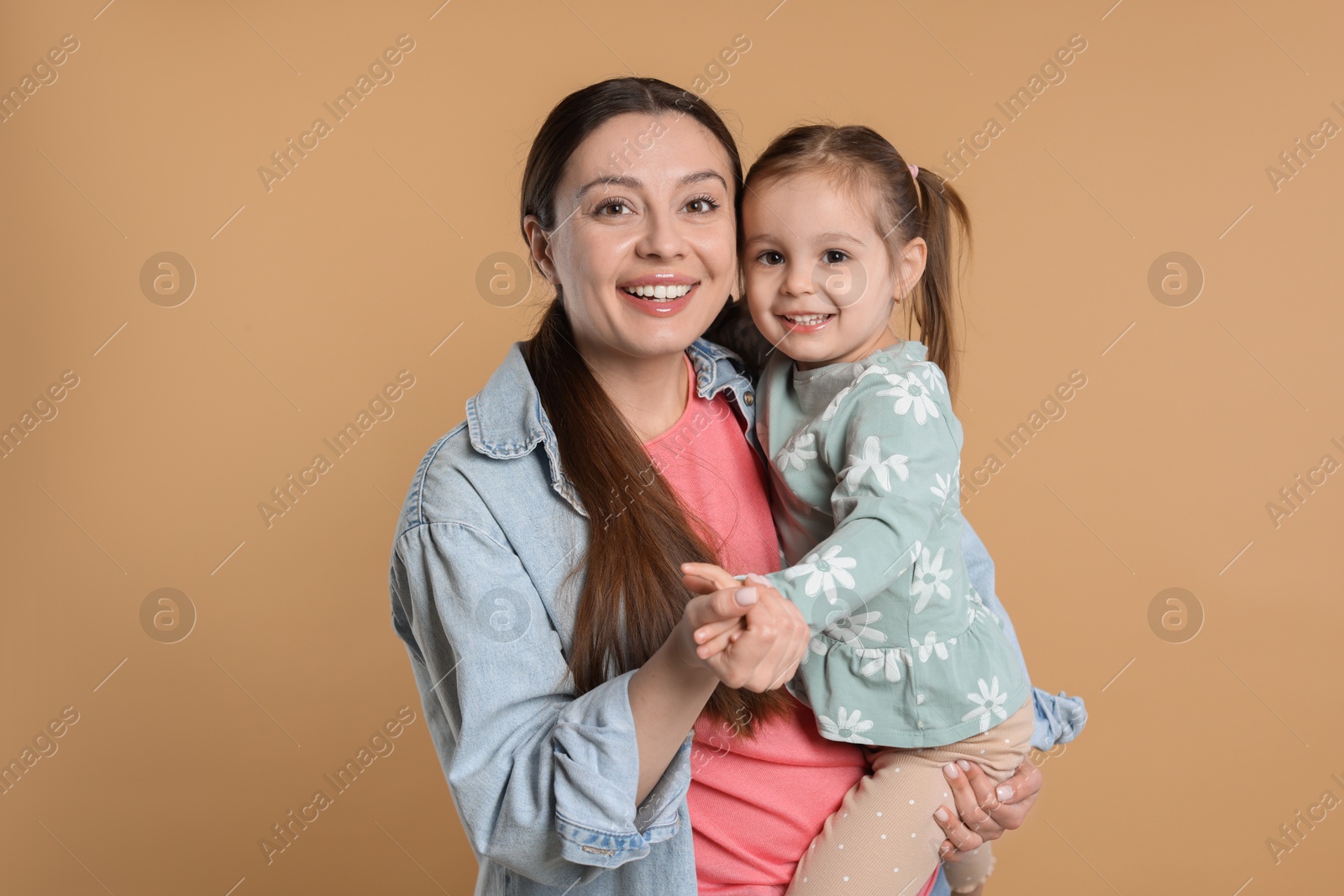 Photo of Portrait of happy mother and her cute little daughter on beige background