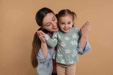 Photo of Portrait of happy mother and her cute little daughter on beige background