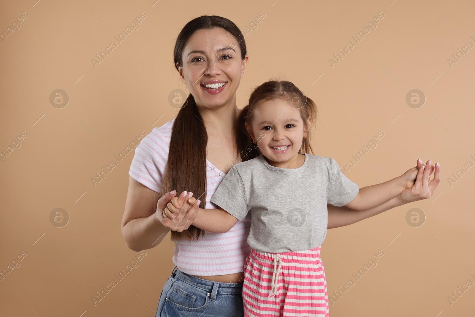 Photo of Portrait of happy mother and her cute little daughter on beige background