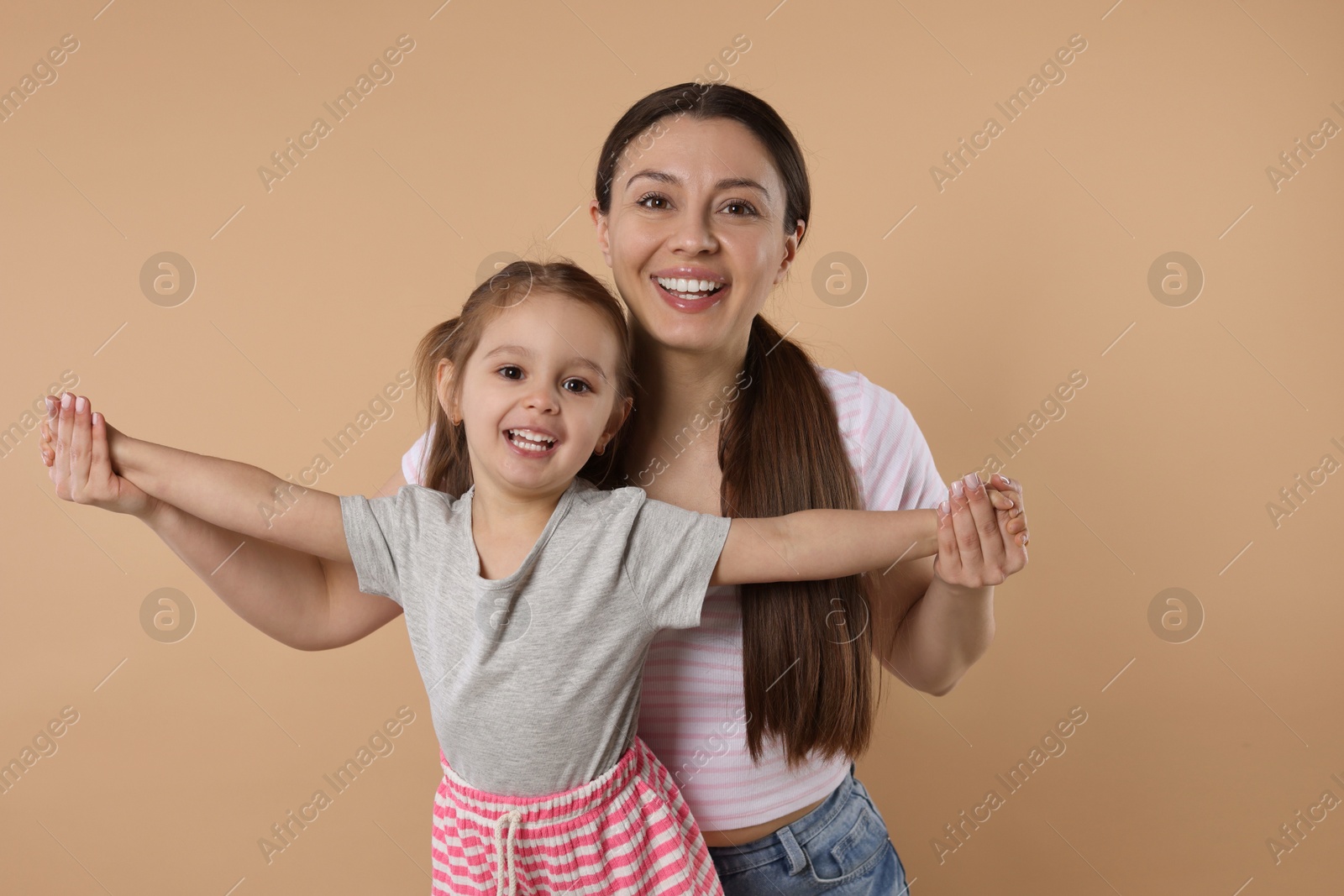 Photo of Portrait of happy mother and her cute little daughter on beige background