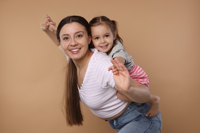 Photo of Portrait of happy mother and her cute little daughter having fun on beige background