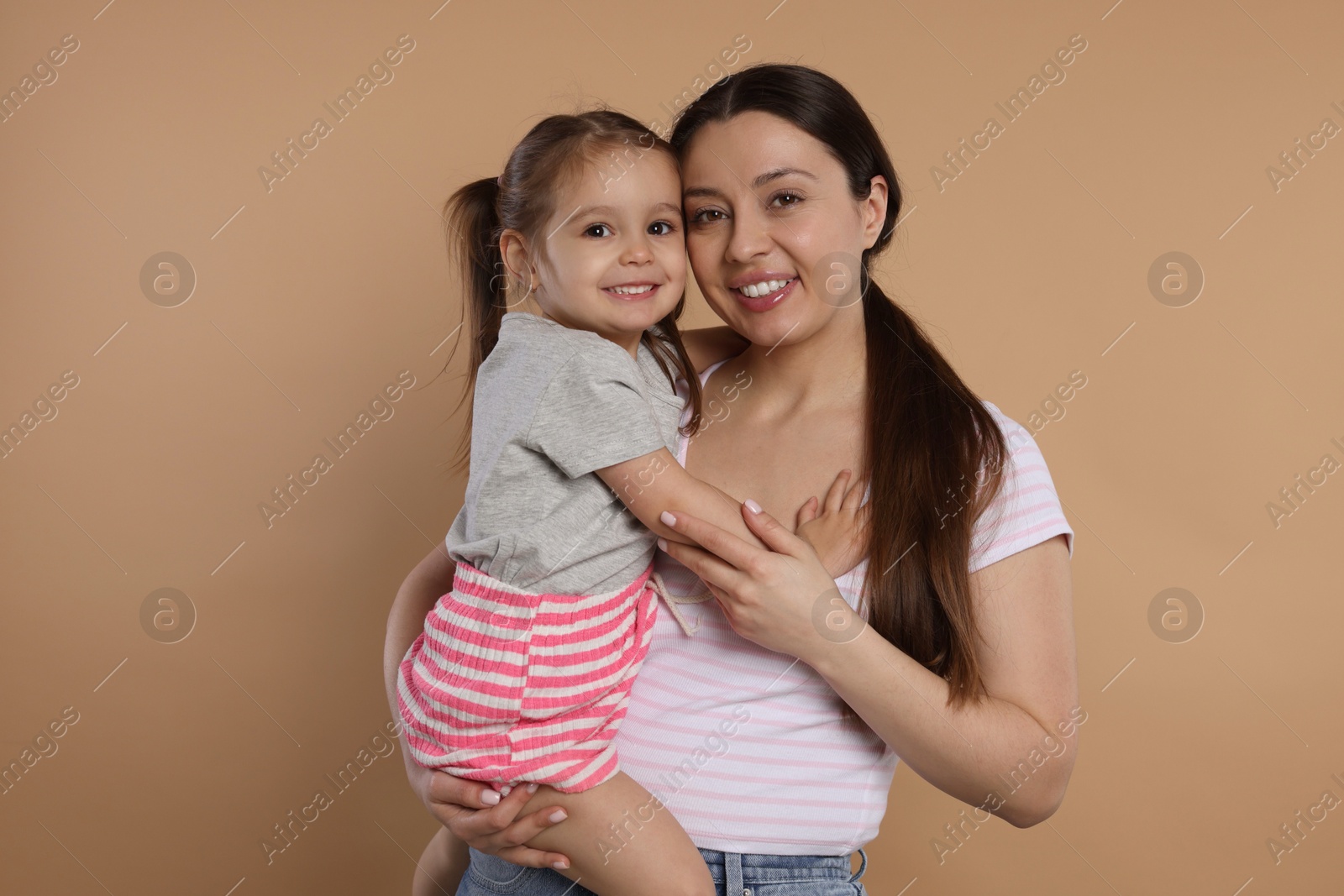 Photo of Portrait of happy mother and her cute little daughter on beige background