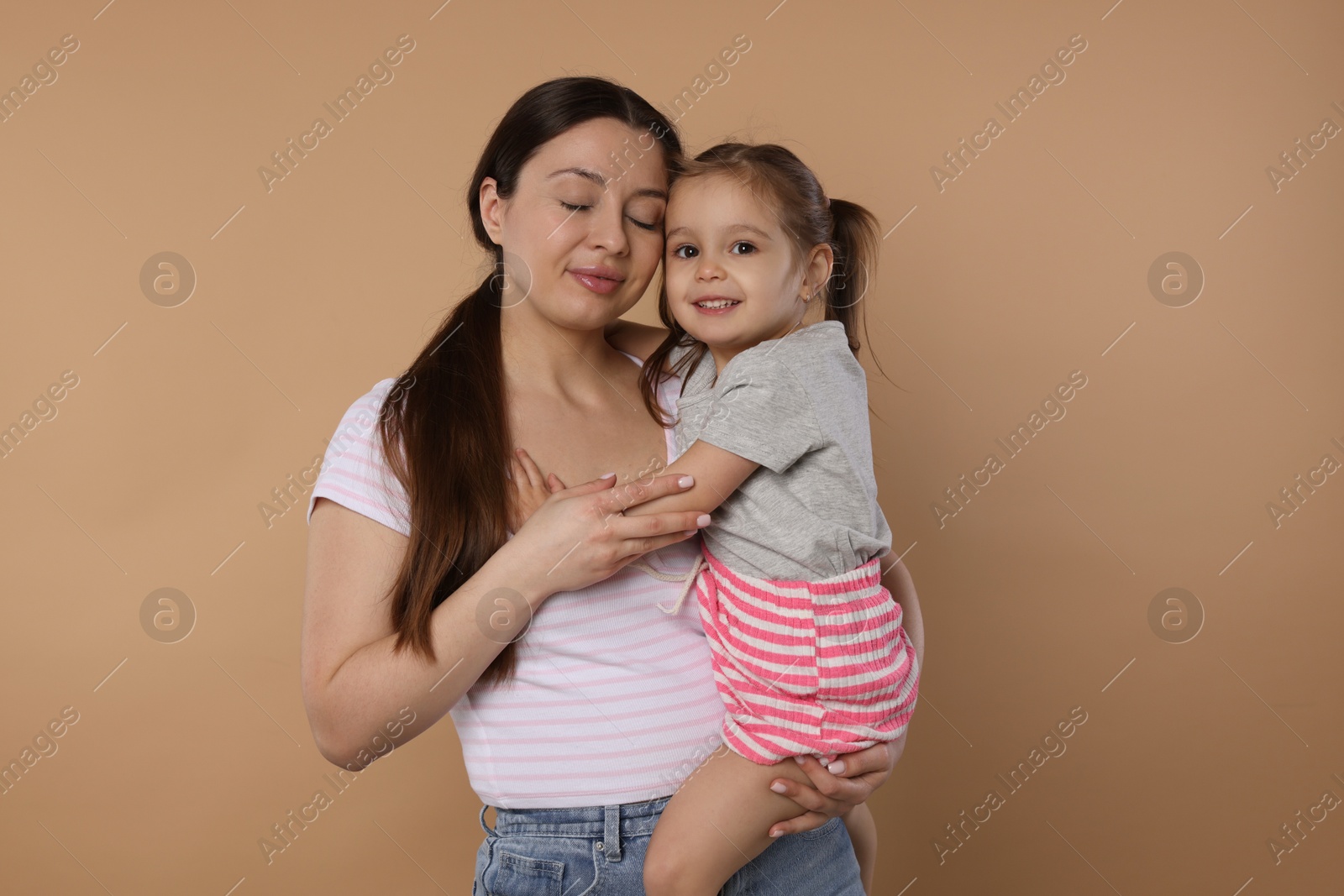 Photo of Portrait of happy mother and her cute little daughter on beige background