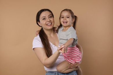 Photo of Portrait of happy mother and her cute little daughter on beige background