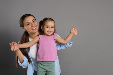 Photo of Portrait of happy mother and her cute little daughter on grey background, space for text