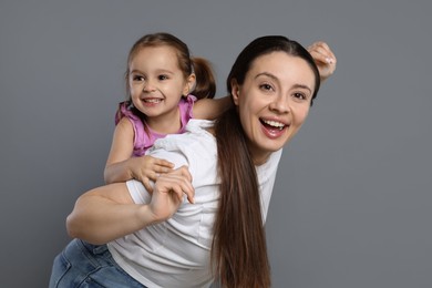 Photo of Portrait of happy mother and her cute little daughter on grey background