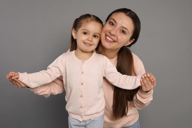 Photo of Portrait of happy mother and her cute little daughter on grey background