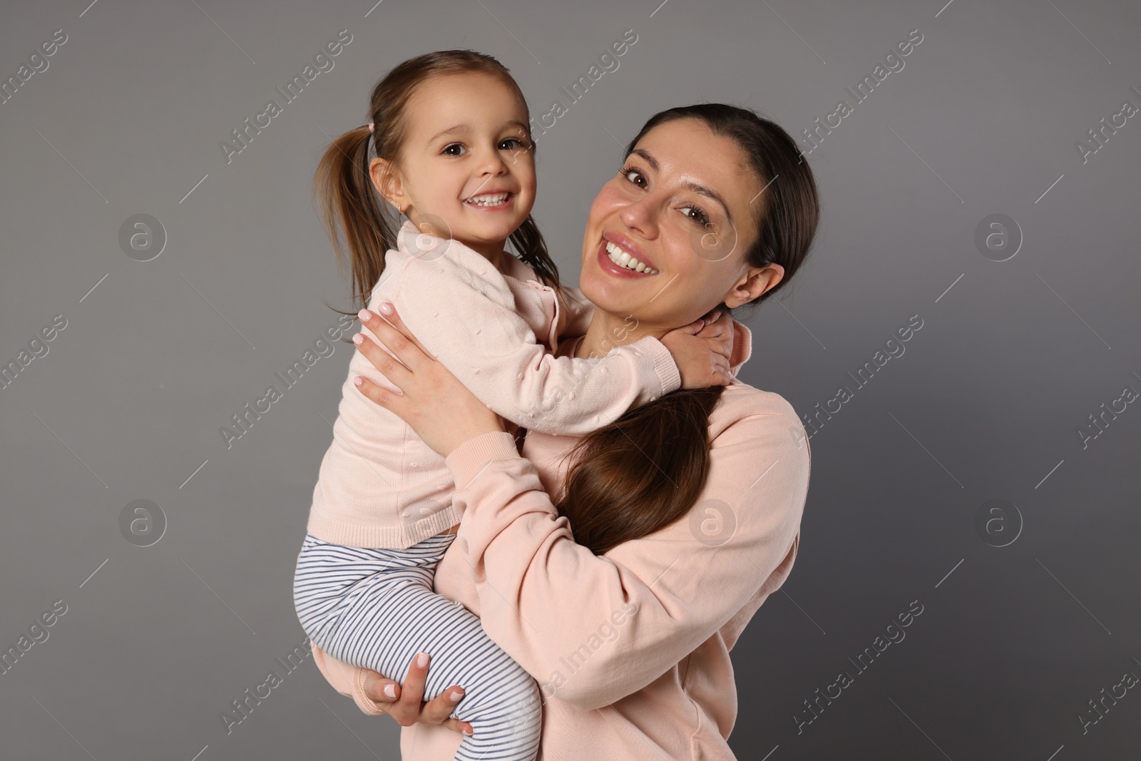 Photo of Portrait of happy mother and her cute little daughter on grey background