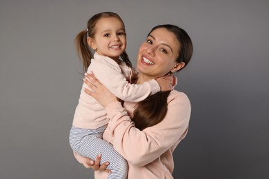 Portrait of happy mother and her cute little daughter on grey background