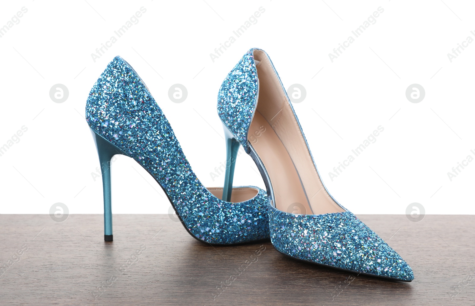 Photo of Beautiful high heeled shoes on wooden table against white background