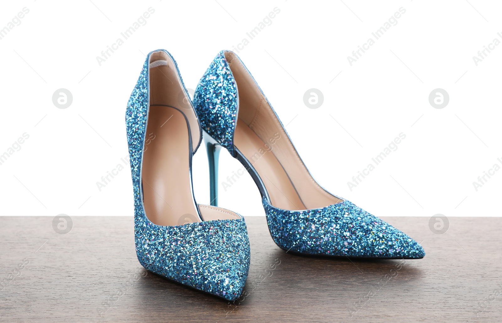 Photo of Beautiful high heeled shoes on wooden table against white background