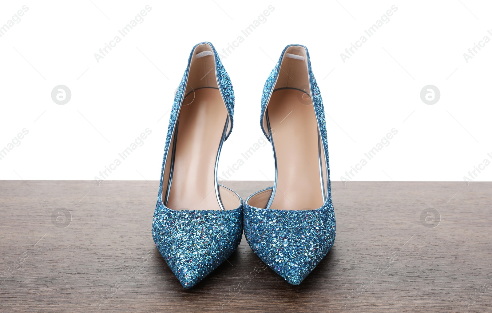 Photo of Beautiful high heeled shoes on wooden table against white background