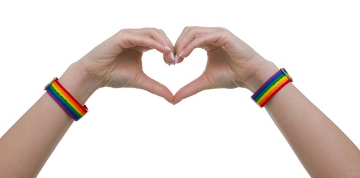 Photo of Woman wearing wristband in LGBT colors and making heart gesture on white background, closeup