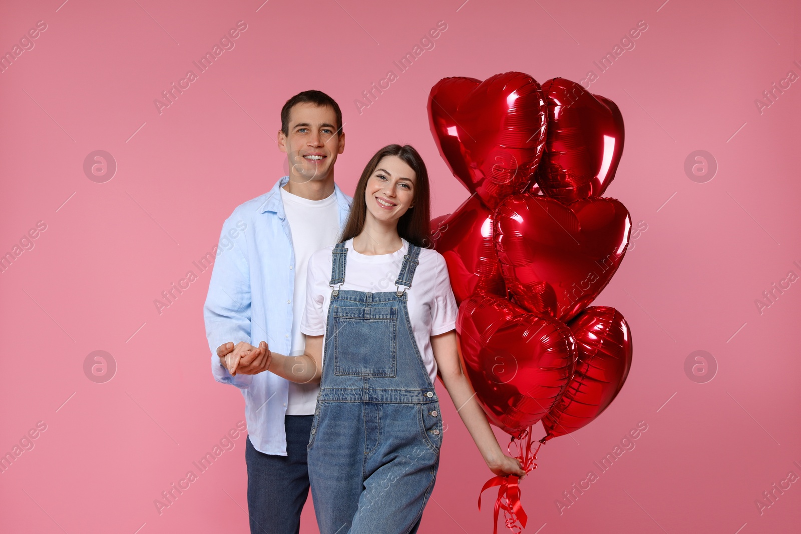 Photo of Lovely couple with heart shaped balloons on pink background. Valentine's day celebration