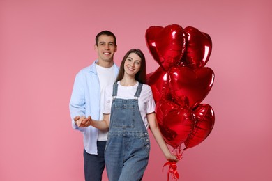 Photo of Lovely couple with heart shaped balloons on pink background. Valentine's day celebration