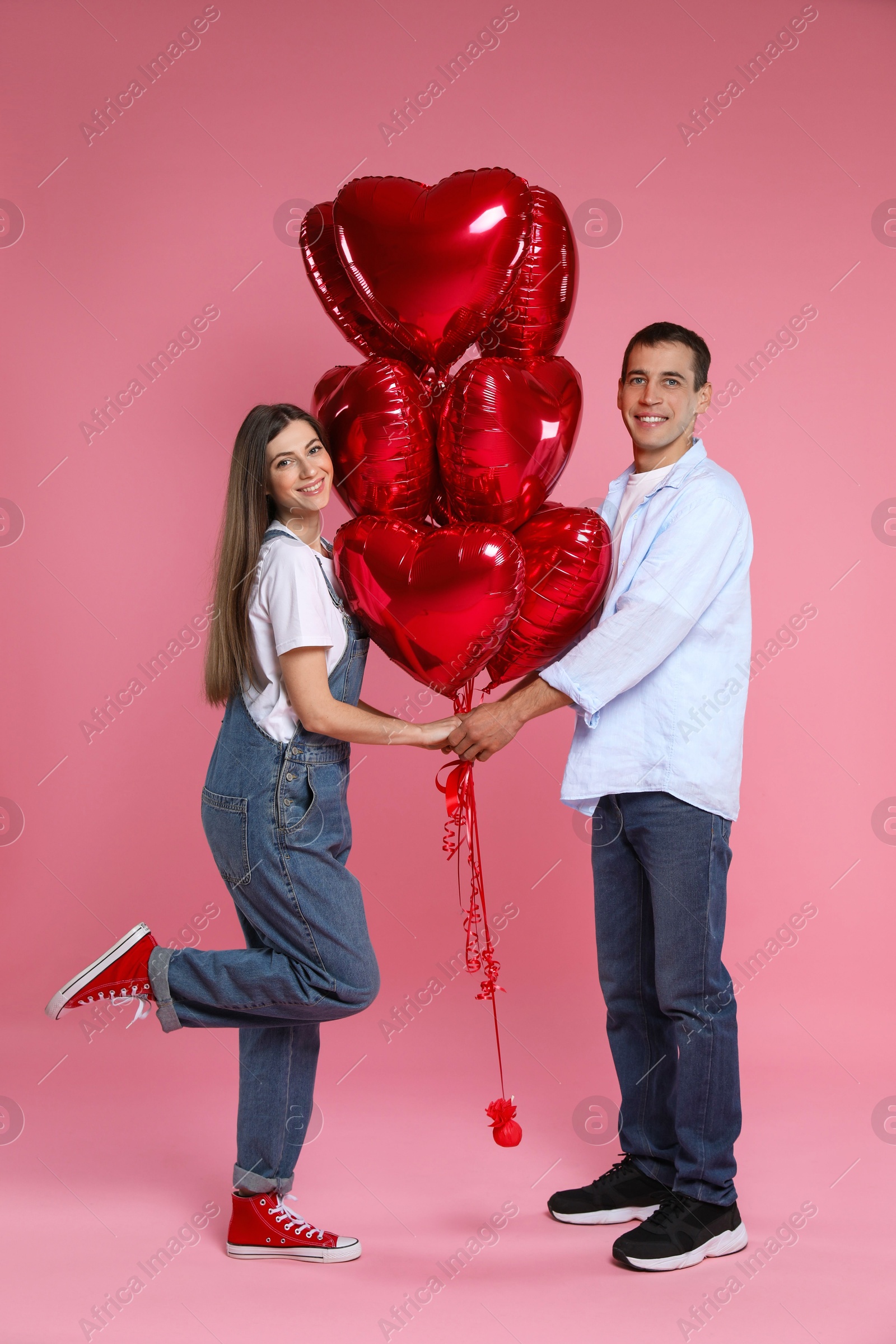 Photo of Lovely couple with heart shaped balloons on pink background. Valentine's day celebration