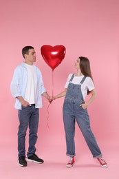 Photo of Lovely couple with heart shaped balloon on pink background. Valentine's day celebration