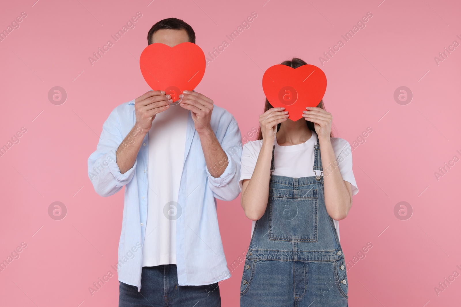 Photo of Lovely couple with paper hearts on pink background. Valentine's day celebration