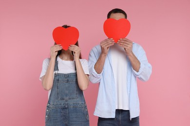 Photo of Lovely couple with paper hearts on pink background. Valentine's day celebration