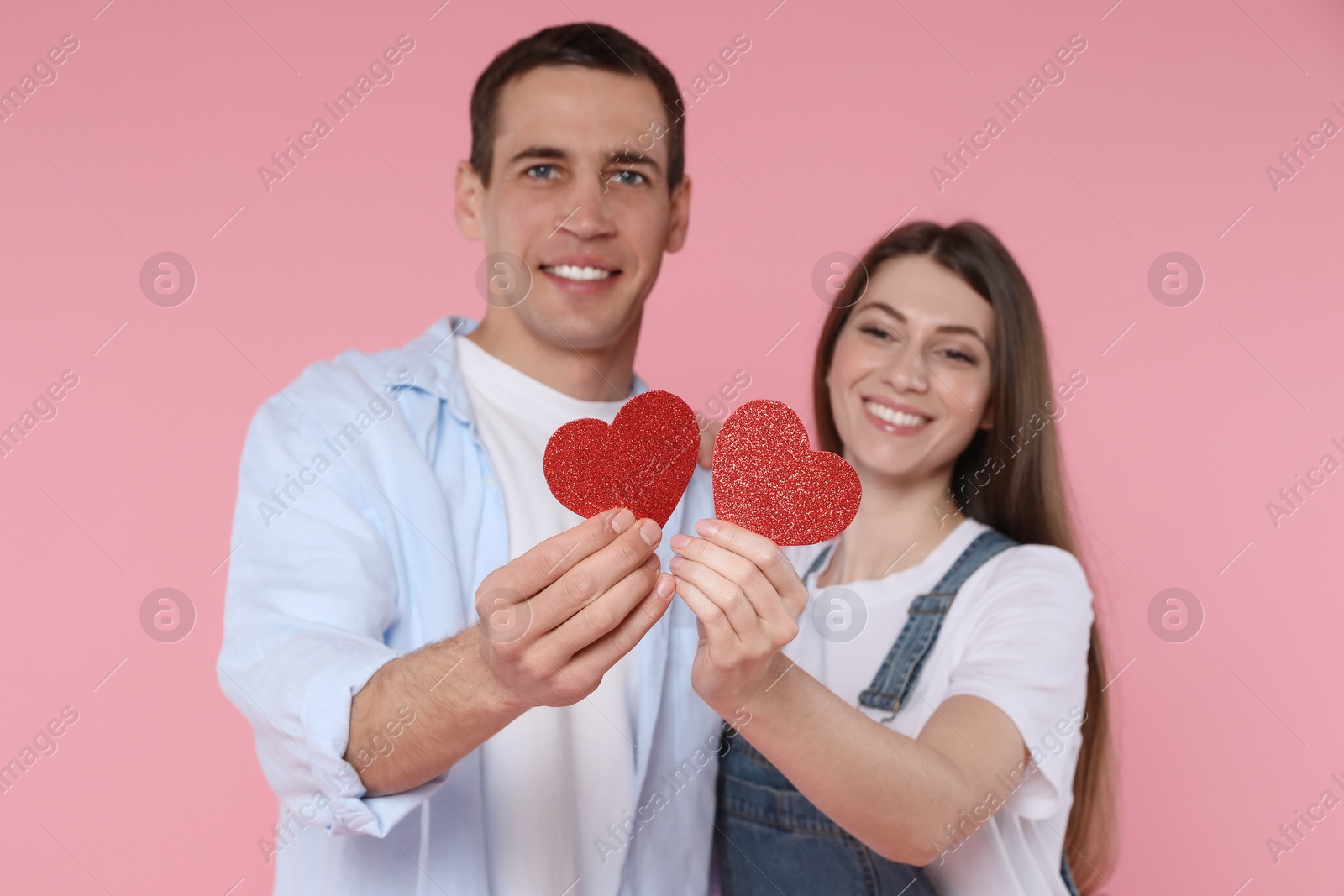 Photo of Lovely couple with paper hearts on pink background, selective focus. Valentine's day celebration