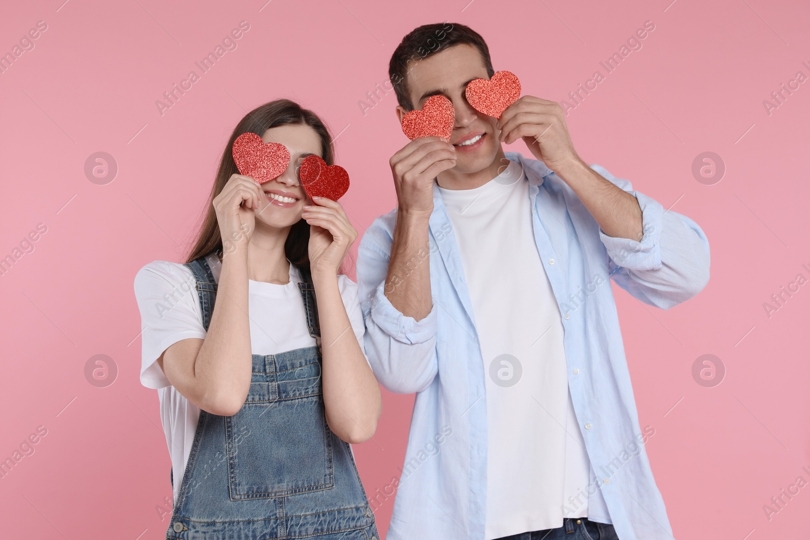 Photo of Lovely couple with paper hearts on pink background. Valentine's day celebration