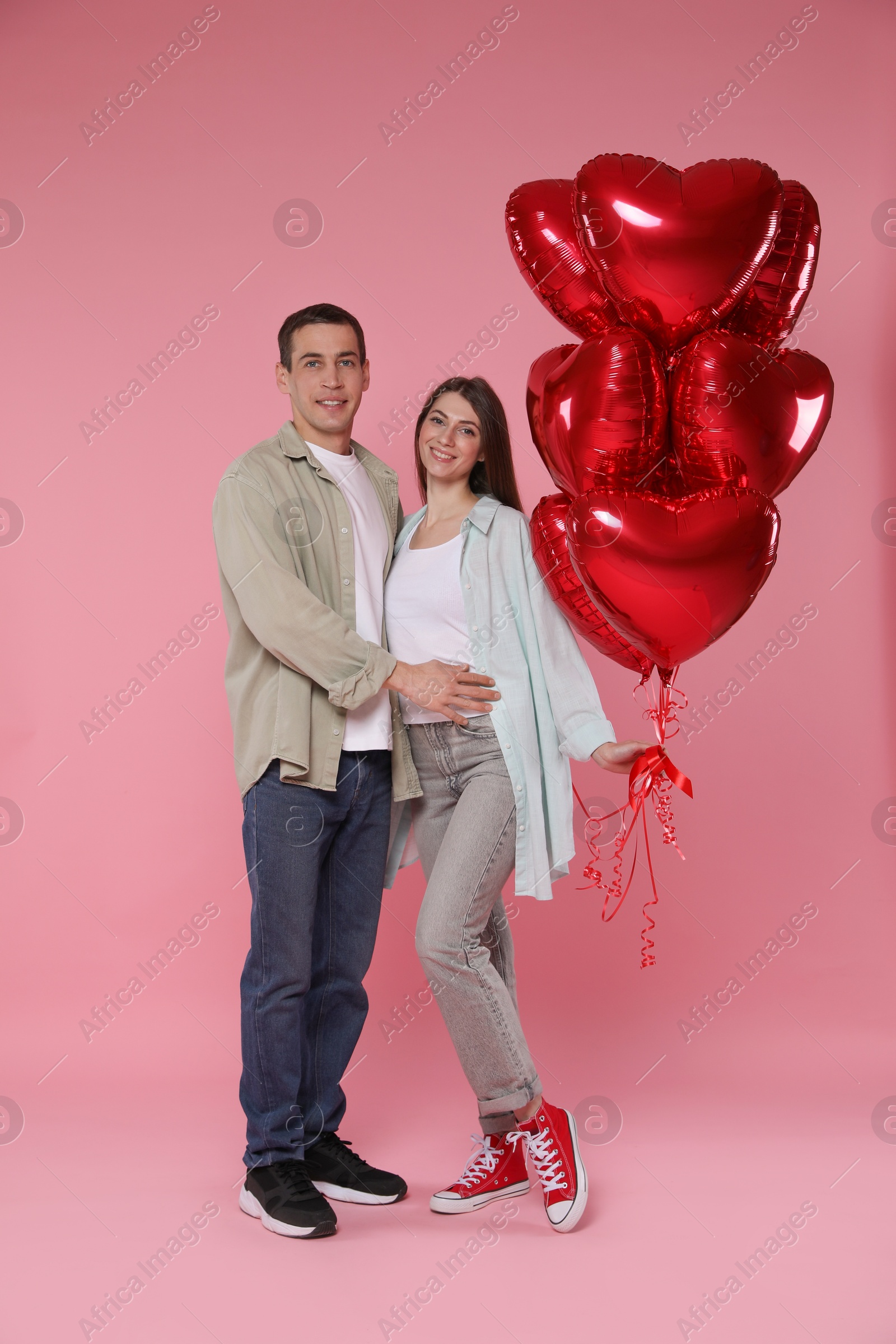 Photo of Lovely couple with heart shaped balloons on pink background. Valentine's day celebration