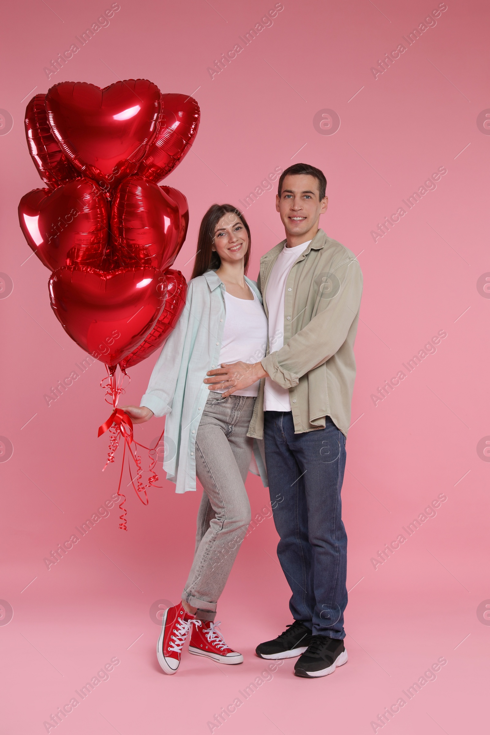 Photo of Lovely couple with heart shaped balloons on pink background. Valentine's day celebration