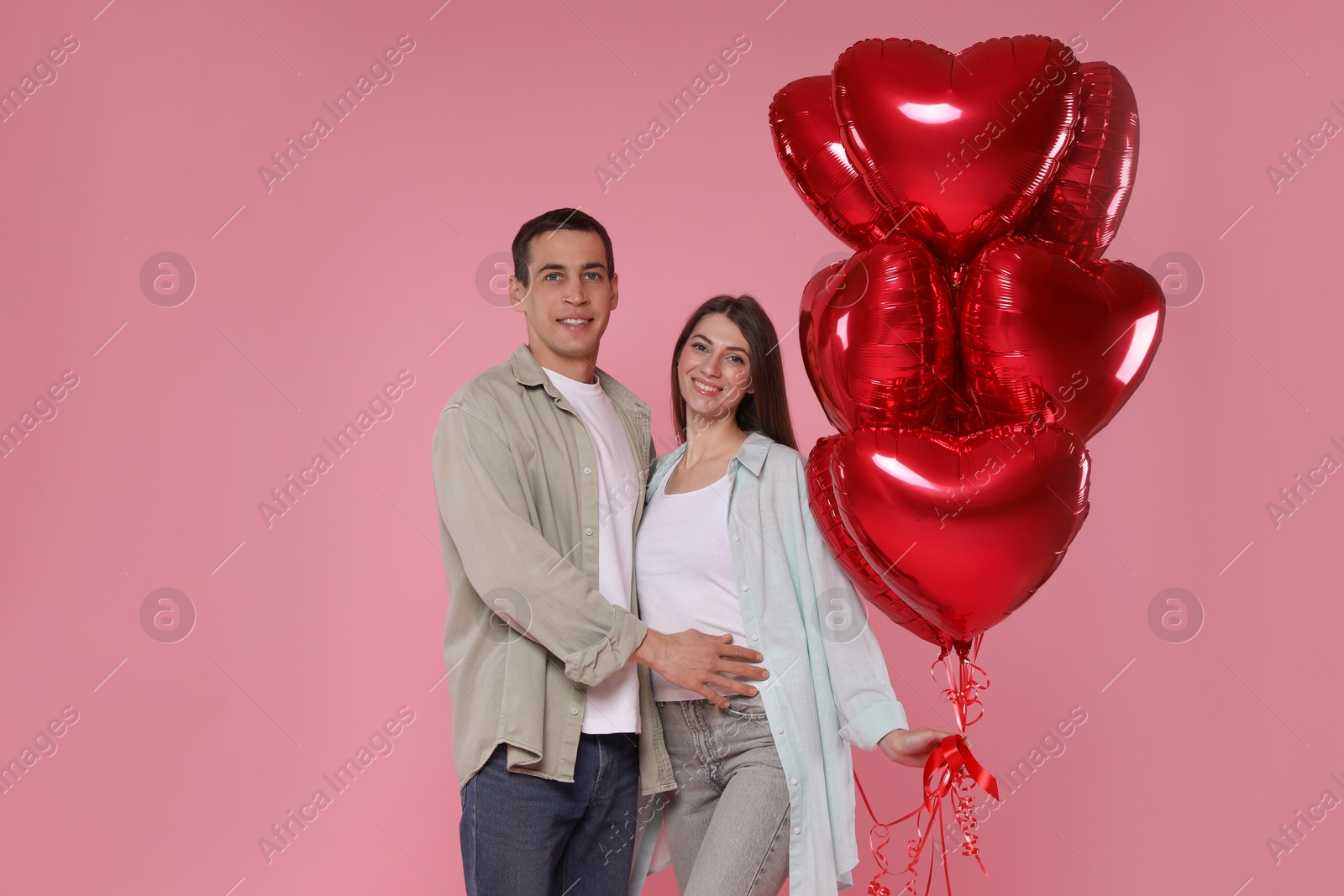 Photo of Lovely couple with heart shaped balloons on pink background. Valentine's day celebration