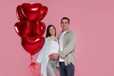 Photo of Lovely couple with heart shaped balloons on pink background. Valentine's day celebration