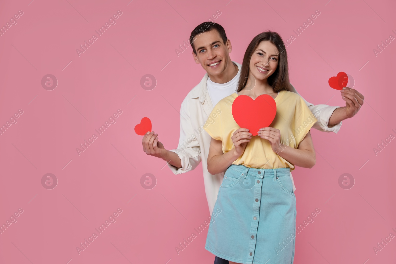 Photo of Lovely couple with paper hearts on pink background, space for text. Valentine's day celebration