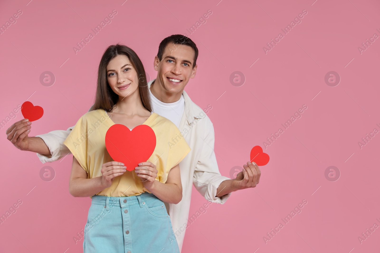 Photo of Lovely couple with paper hearts on pink background, space for text. Valentine's day celebration