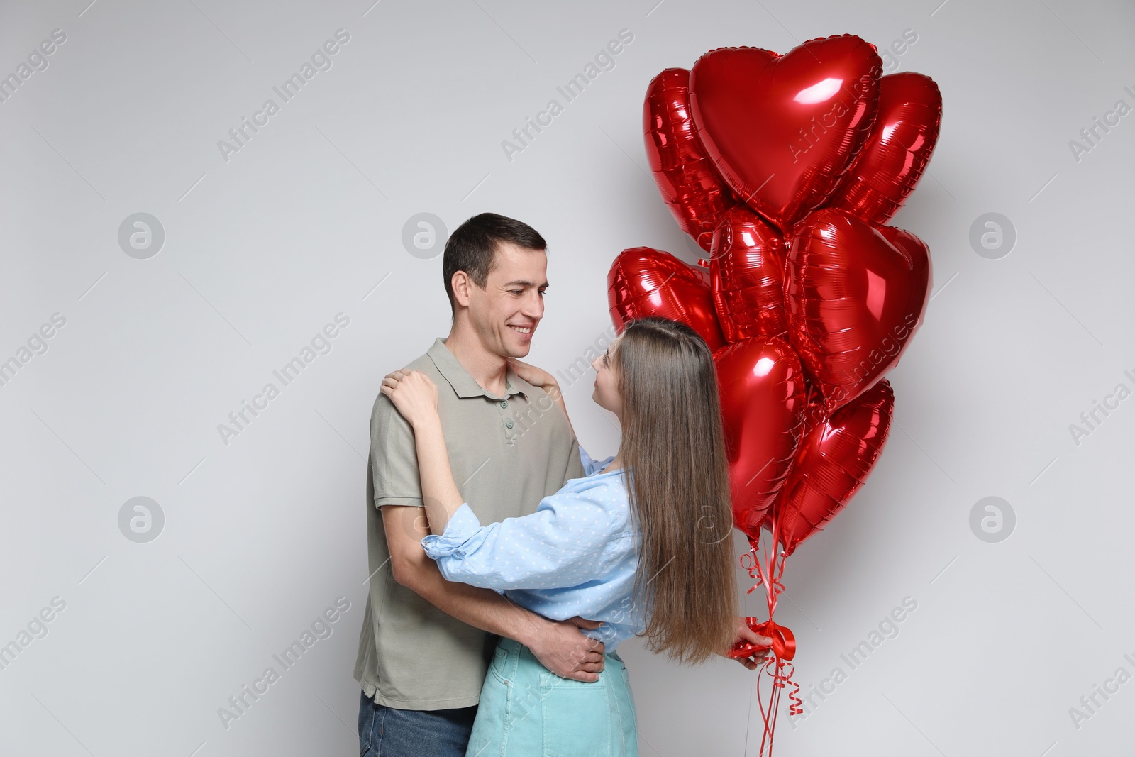 Photo of Lovely couple with heart shaped balloons on light background. Valentine's day celebration