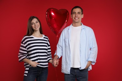 Photo of Lovely couple with heart shaped balloon on red background. Valentine's day celebration