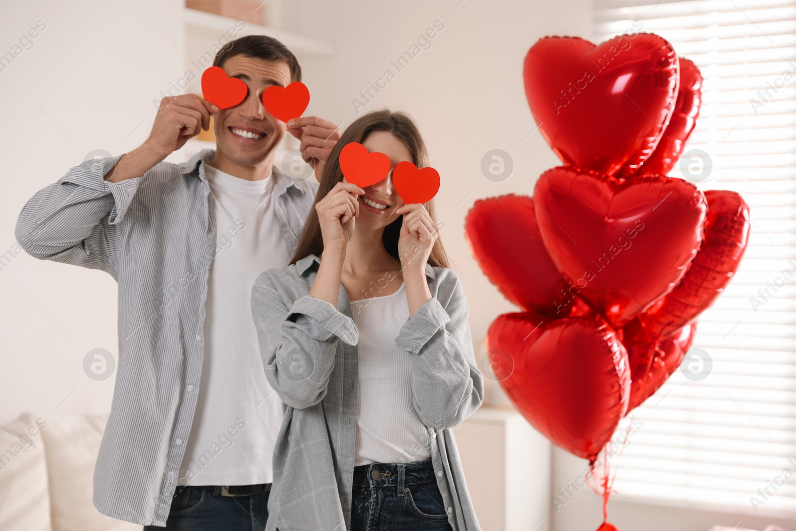 Photo of Lovely couple with paper hearts indoors. Valentine's day celebration