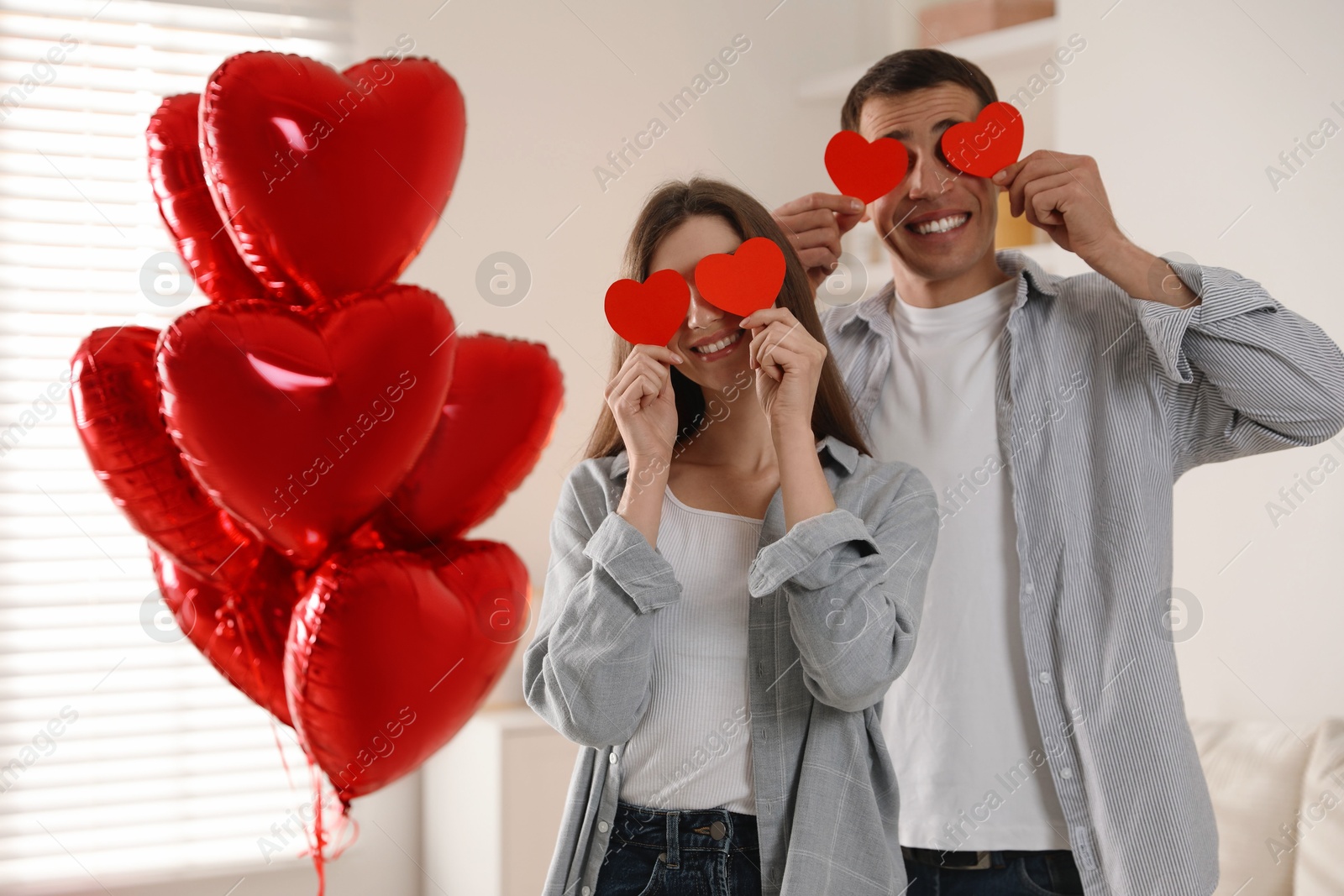 Photo of Lovely couple with paper hearts indoors. Valentine's day celebration