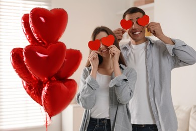 Photo of Lovely couple with paper hearts indoors. Valentine's day celebration