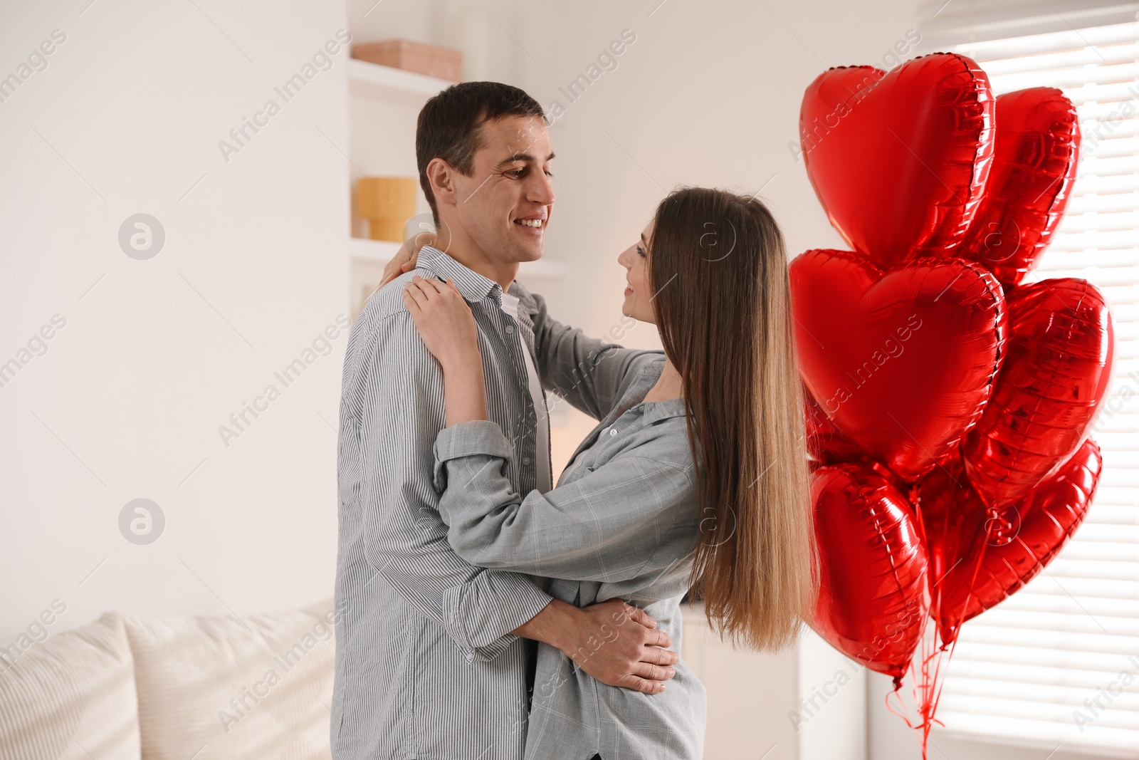 Photo of Lovely couple near heart shaped balloons indoors. Valentine's day celebration