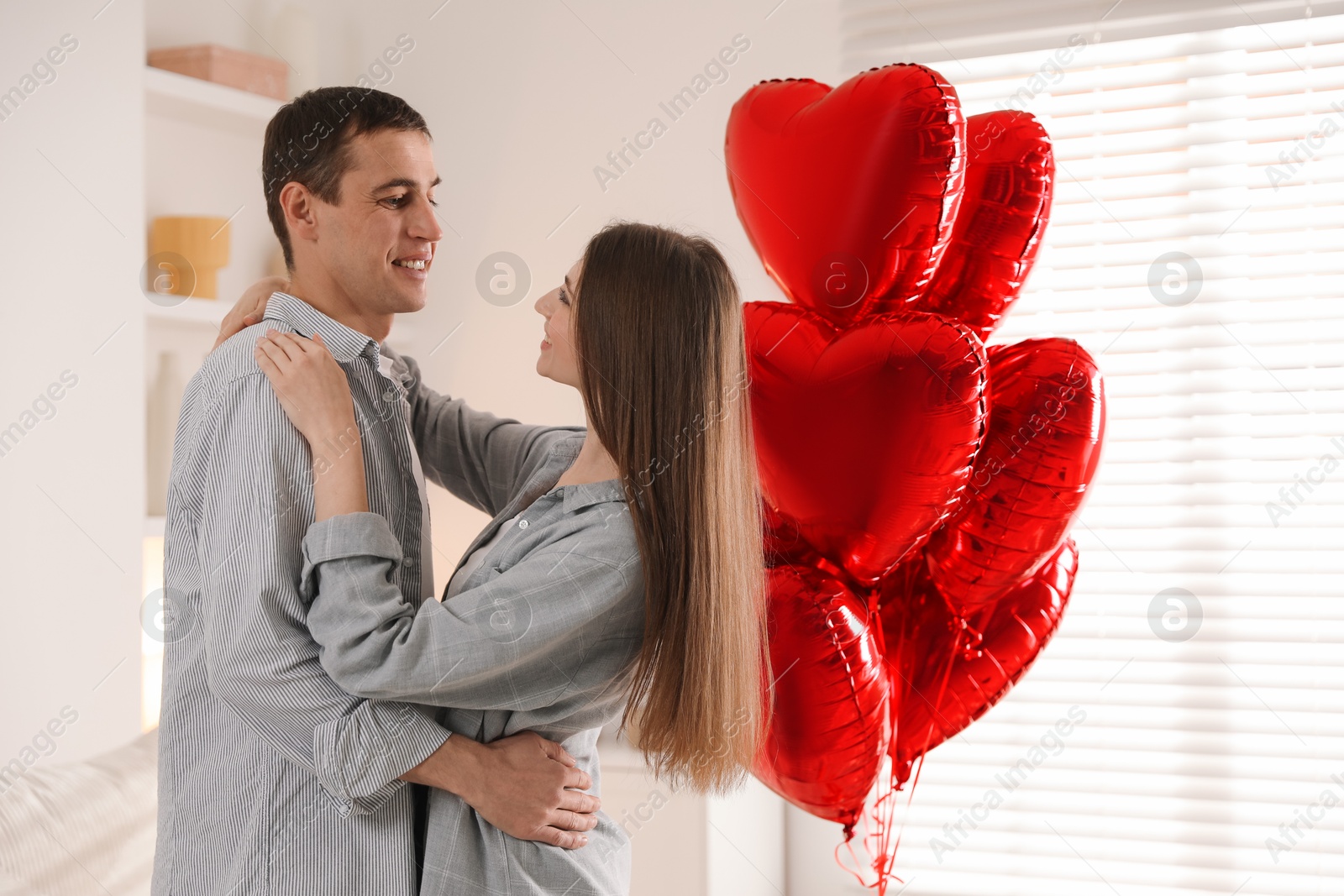 Photo of Lovely couple near heart shaped balloons indoors. Valentine's day celebration